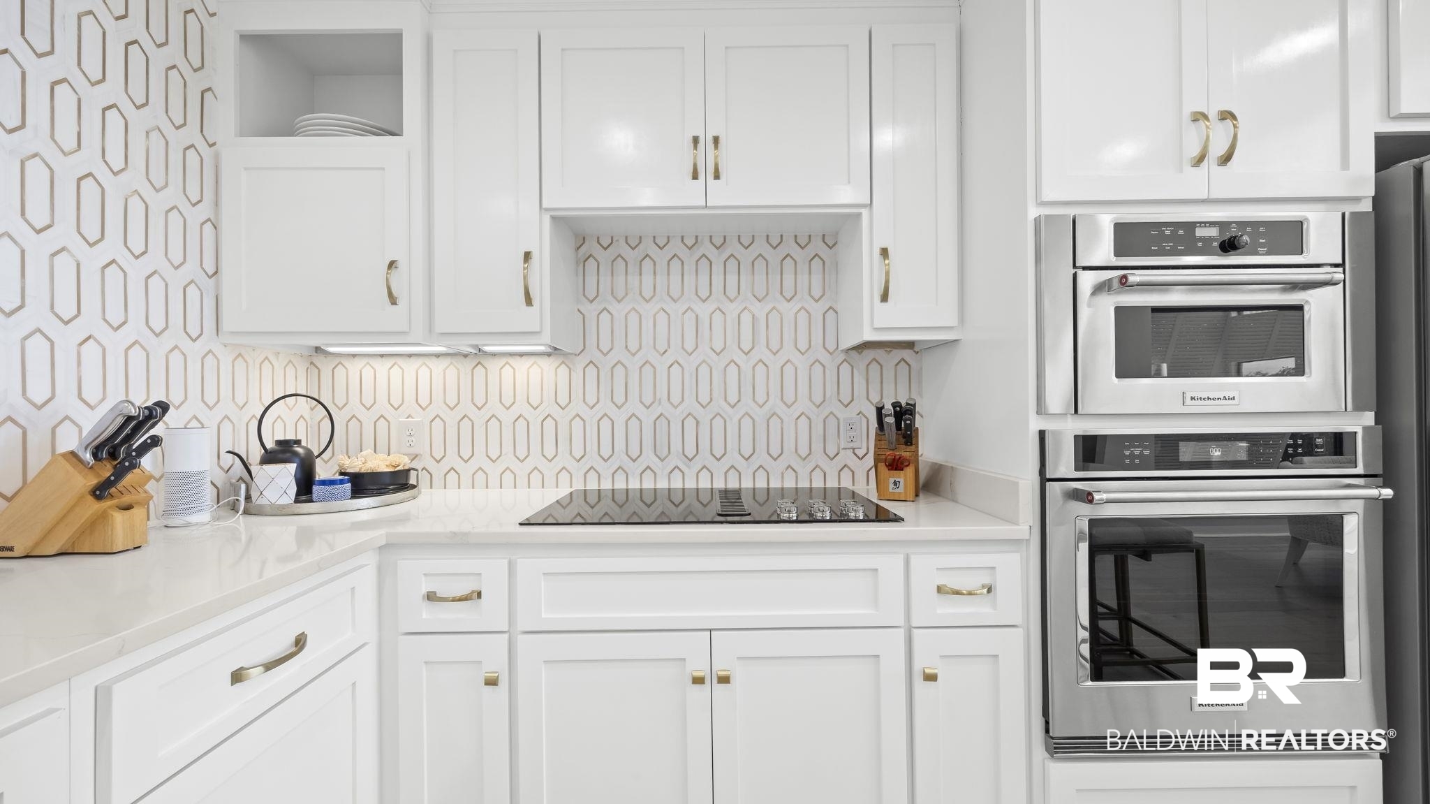 30194 River Road Orange Beach, AL 36561 - Photo 8 of 45 Kitchen with white cabinets, light stone countertops, double oven, tasteful backsplash, and black electric cooktop