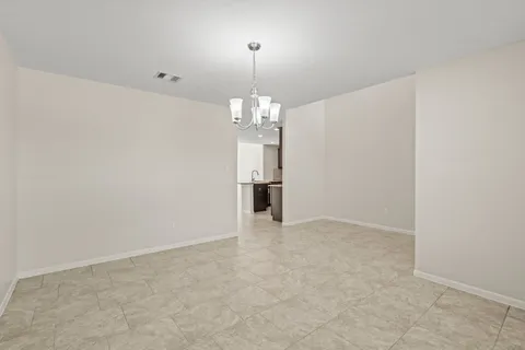 an empty room with chandelier and windows