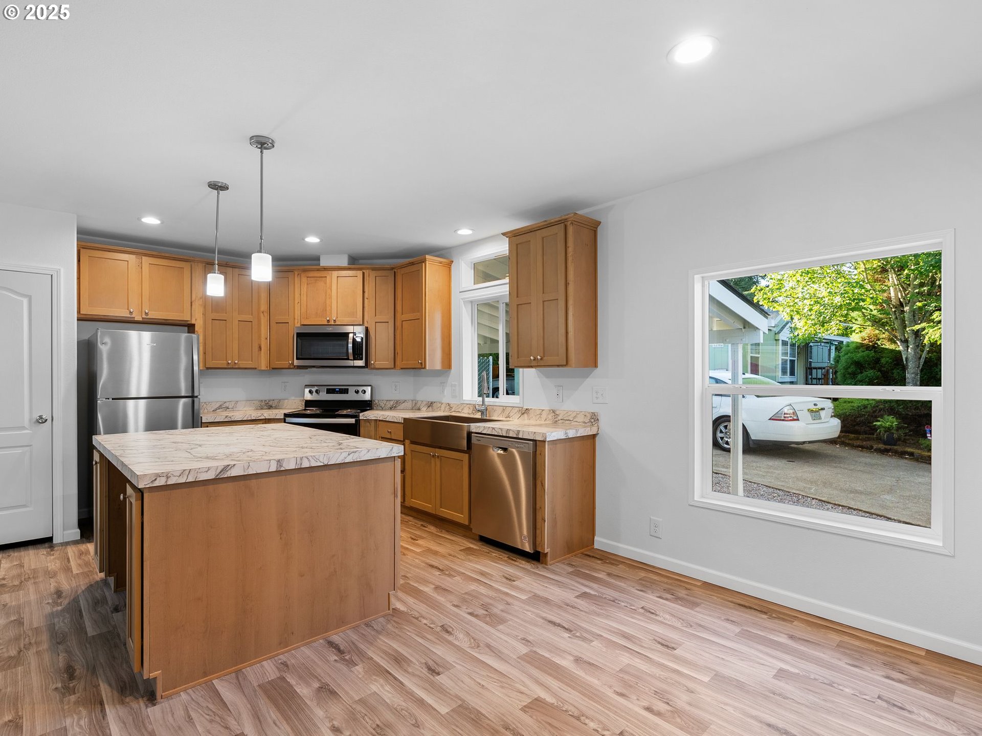12904 Southeast Ramona Street Portland, OR 97236 - Photo 12 of 35 a kitchen with stainless steel appliances granite countertop a refrigerator a sink dishwasher a stove and a dining table with wooden floor