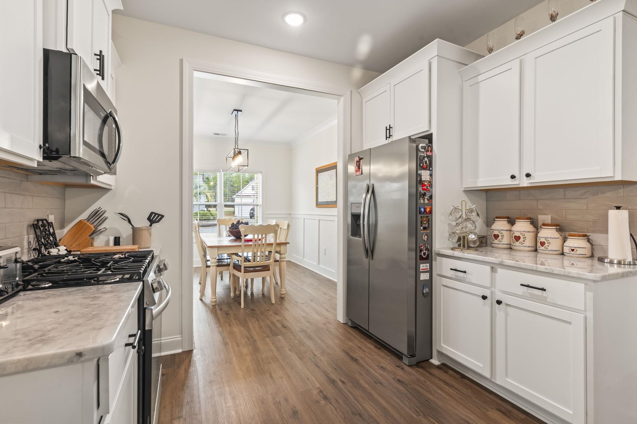 207 Putney Court Conway, SC 29526 - Photo 10 of 38 Kitchen with stainless steel appliances, tasteful backsplash, white cabinetry, dark wood-style floors, and decorative light fixtures