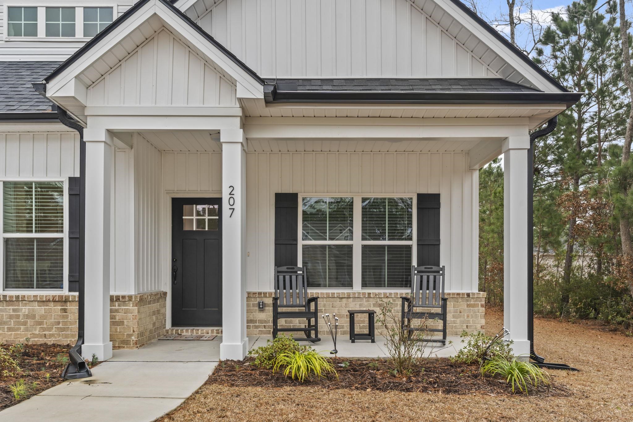 207 Putney Court Conway, SC 29526 - Photo 2 of 38 View of exterior entry with board and batten siding, a porch, a shingled roof, and brick siding