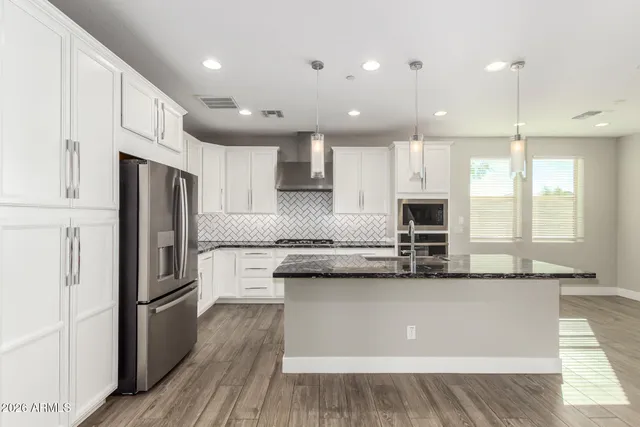 a kitchen with stainless steel appliances granite countertop a refrigerator a sink and a stove