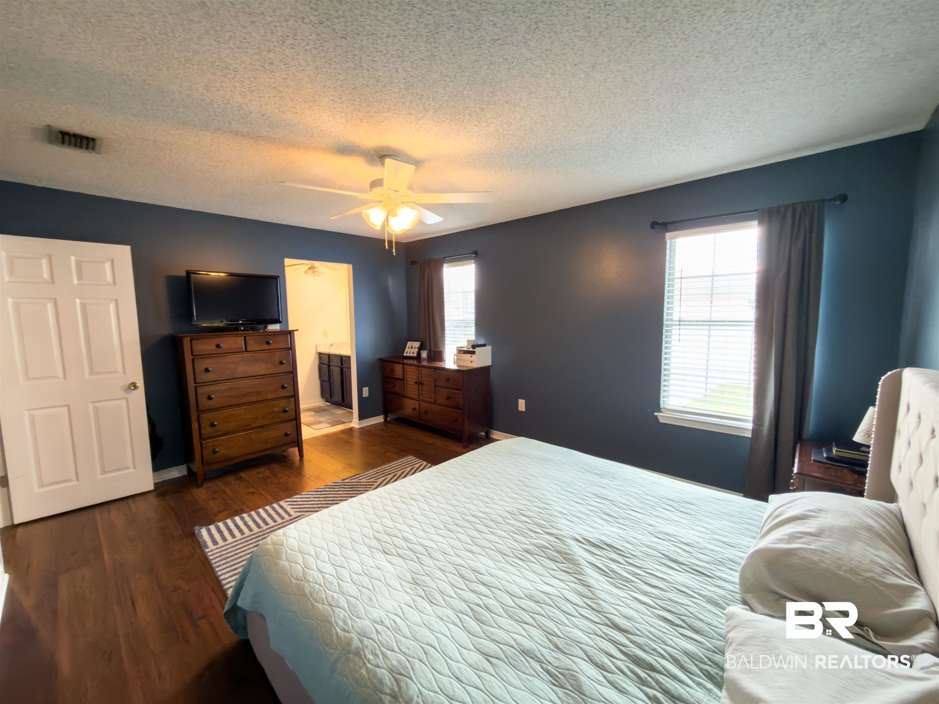 129 Pennbrooke Loop Foley, AL 36535 - Photo 25 of 44 Bedroom featuring dark wood-style flooring, ensuite bathroom, a ceiling fan, and a textured ceiling