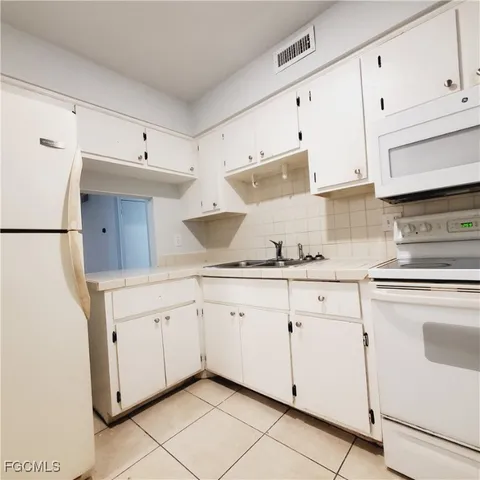 a kitchen with granite countertop white cabinets white stainless steel appliances with a sink and dishwasher
