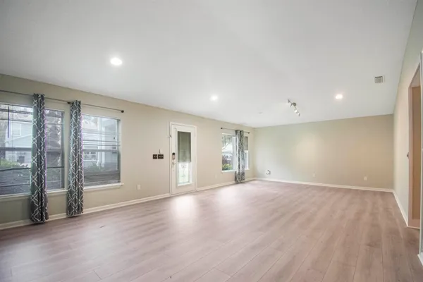 an empty room with wooden floor and windows