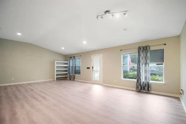 a view of an empty room with a window and wooden floor