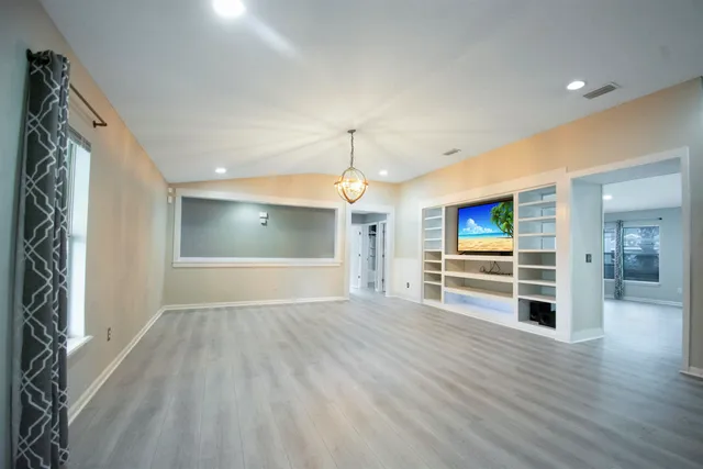 a view of empty room with wooden floor and window