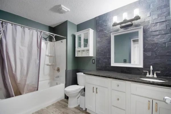 a bathroom with a granite countertop sink toilet and shower