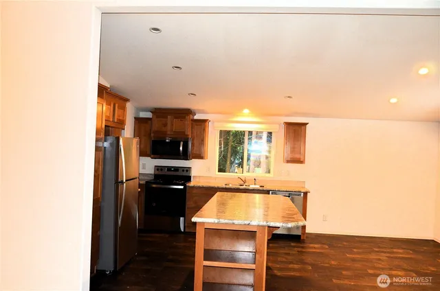 a room with kitchen island stainless steel appliances a stove and a refrigerator
