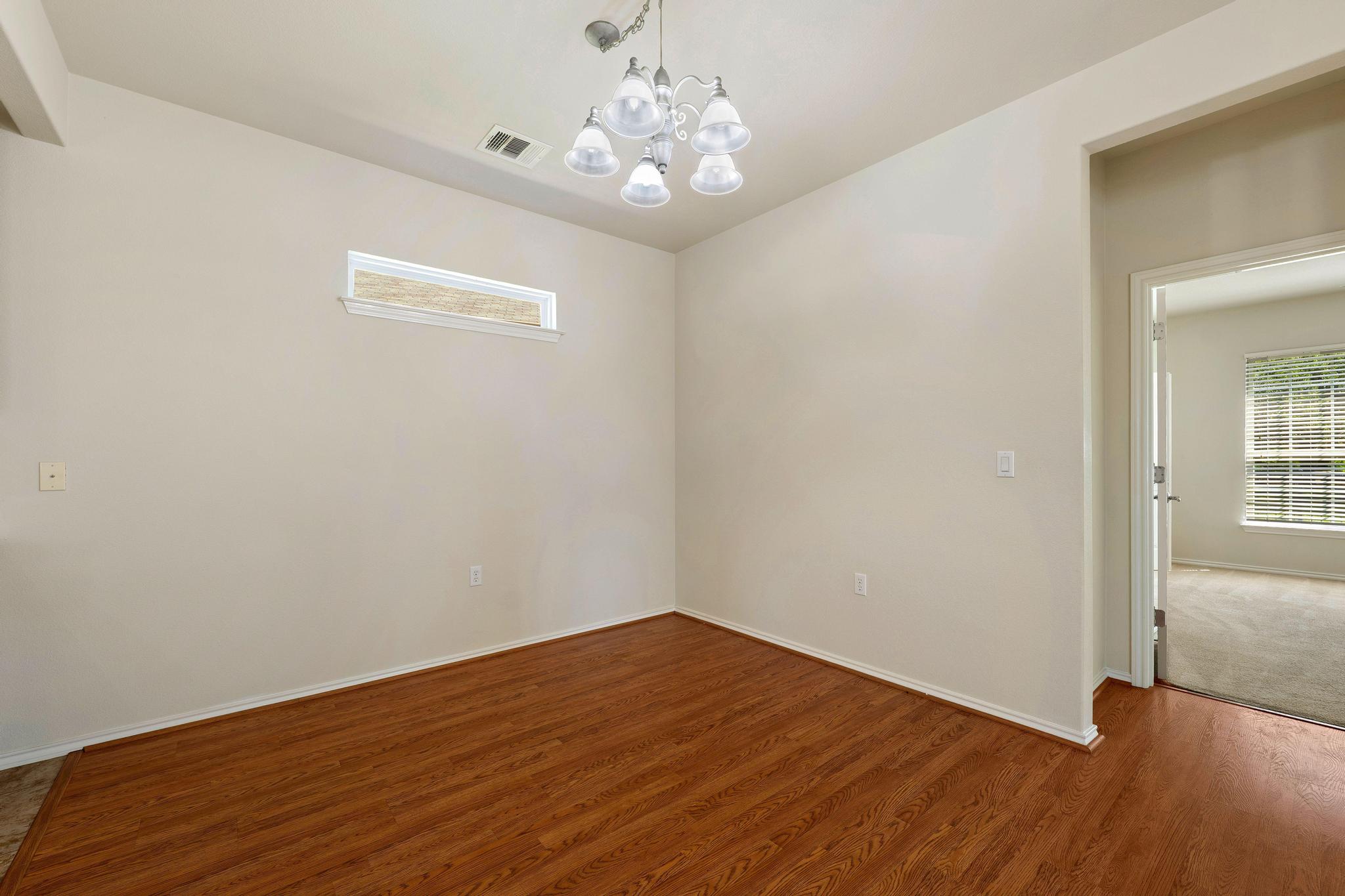 520 Mill Pond Path Georgetown, TX 78633 - Photo 22 of 38 A refined dining space features durable wood flooring and a classic chandelier, offering a bright, versatile interior.