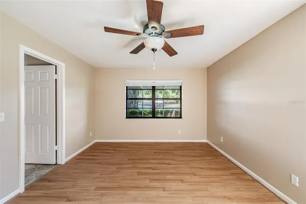 a view of empty room with wooden floor and fan