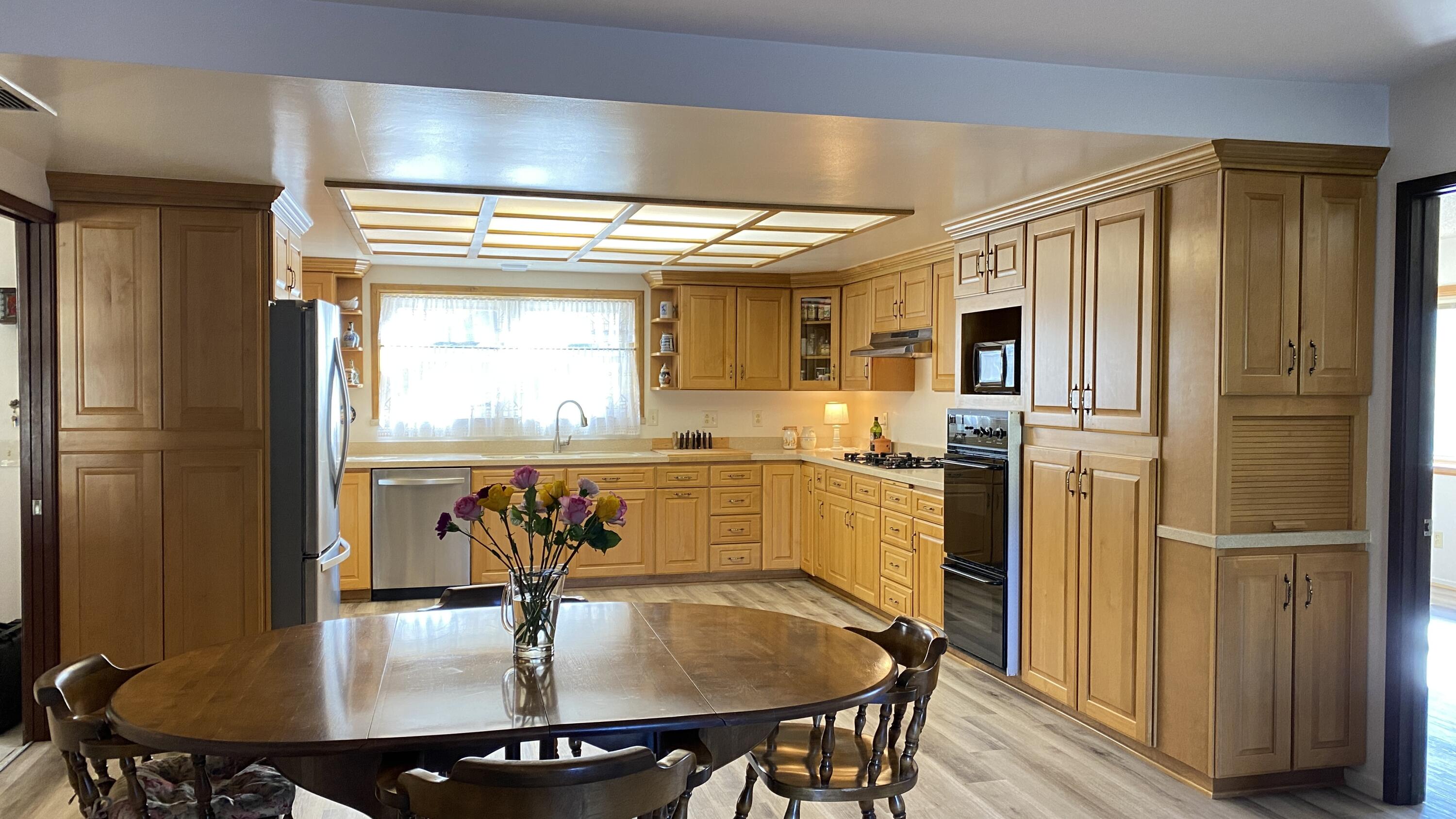 1401 San Miguelito Road Lompoc, CA 93436 - Photo 21 of 61 a kitchen with stainless steel appliances kitchen island granite countertop a refrigerator a stove and a dining table with wooden floor