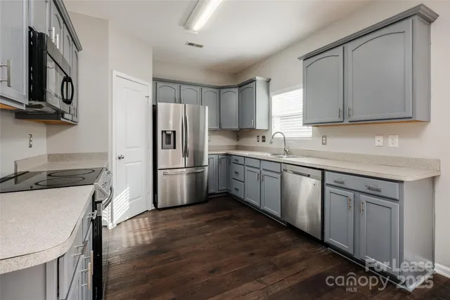 a kitchen with a sink cabinets stainless steel appliances and a window
