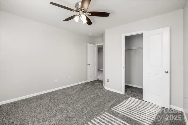 an empty room with closet and a ceiling fan