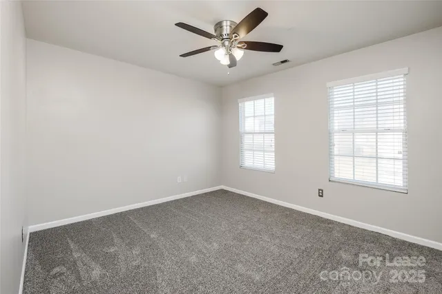 an empty room with windows and ceiling fan