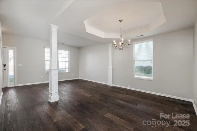 a view of a room with wooden floor chandelier and windows