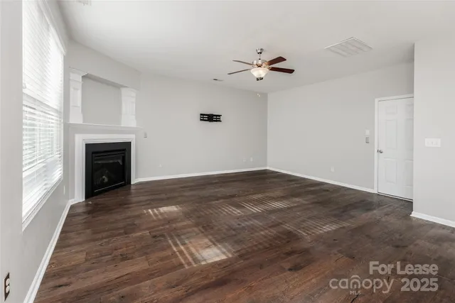 a view of empty room with wooden floor and fireplace