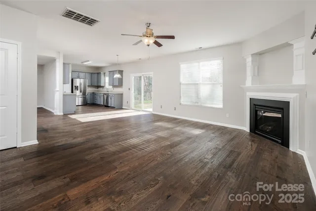 a view of a livingroom with a fireplace a ceiling fan and windows