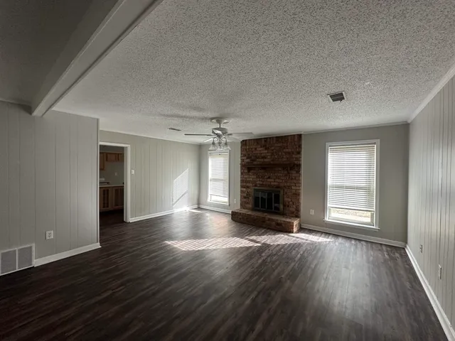 an empty room with wooden floor fireplace and window
