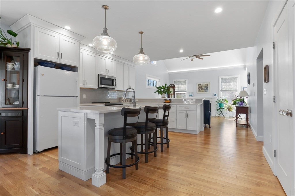18 Primrose Lane, Unit 18 Ipswich, MA 01938 - Photo 8 of 39 a kitchen with stainless steel appliances kitchen island granite countertop a refrigerator a stove and a dining table with wooden floor