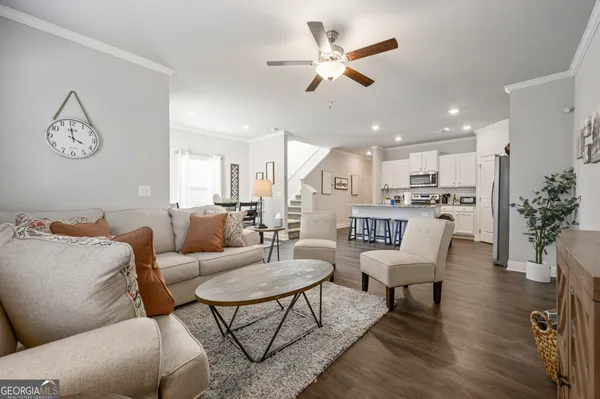 a living room with furniture kitchen view and a chandelier