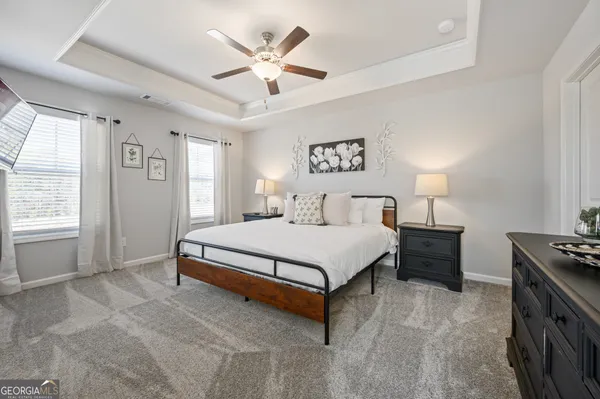 a spacious bedroom with a bed a ceiling fan and a window