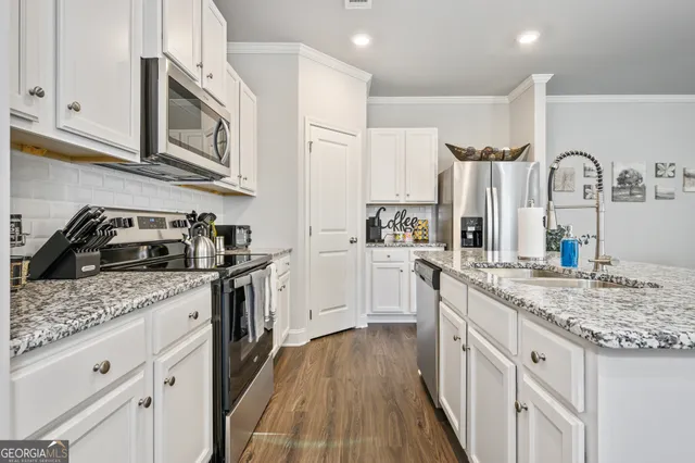 a kitchen with stainless steel appliances granite countertop a sink a stove and cabinets