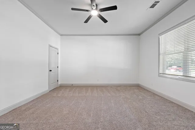an empty room with windows and fan