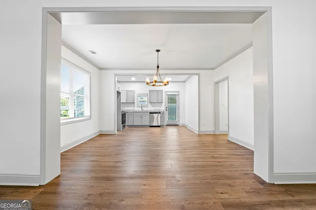 a view of an empty room with window and wooden floor