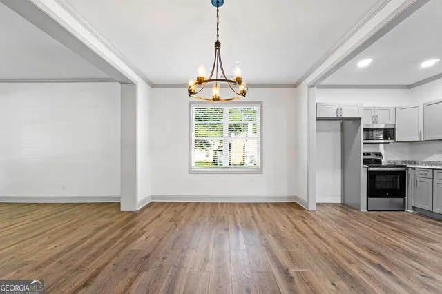 a view of empty room with wooden floor and kitchen view