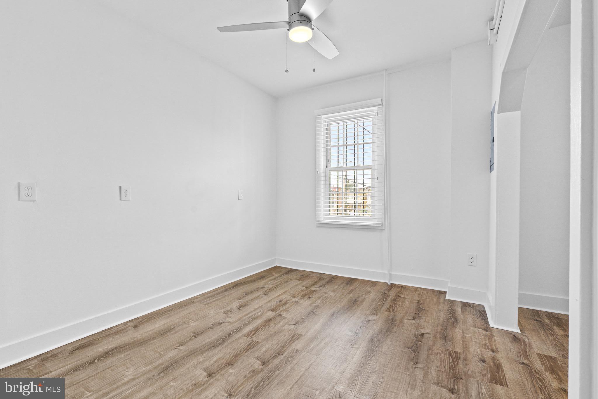 1308 West Lexington Street, Unit 2R Baltimore, MD 21223 - Photo 7 of 12 an empty room with wooden floor fan and windows