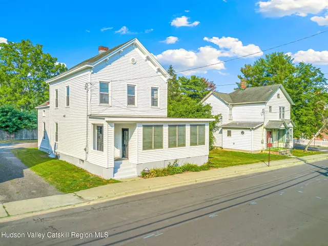a front view of a house with a garden and trees