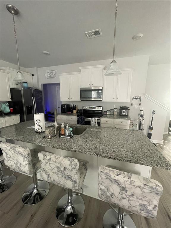 a kitchen with stainless steel appliances granite countertop a sink a stove white cabinets a dining table and chairs