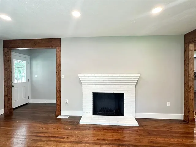 a view of an empty room with wooden floor and a fireplace