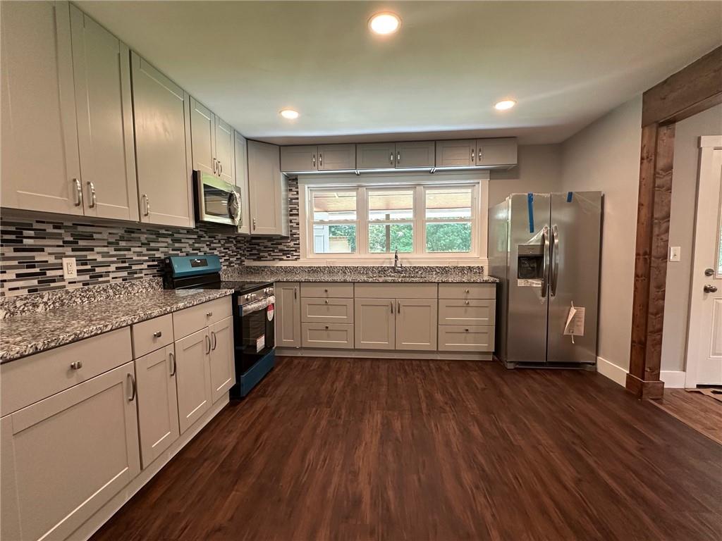 6538 North Sweetwater Road Lithia Springs, GA 30122 - Photo 4 of 16 a kitchen with stainless steel appliances granite countertop a refrigerator a sink dishwasher a stove and white countertops with wooden floor