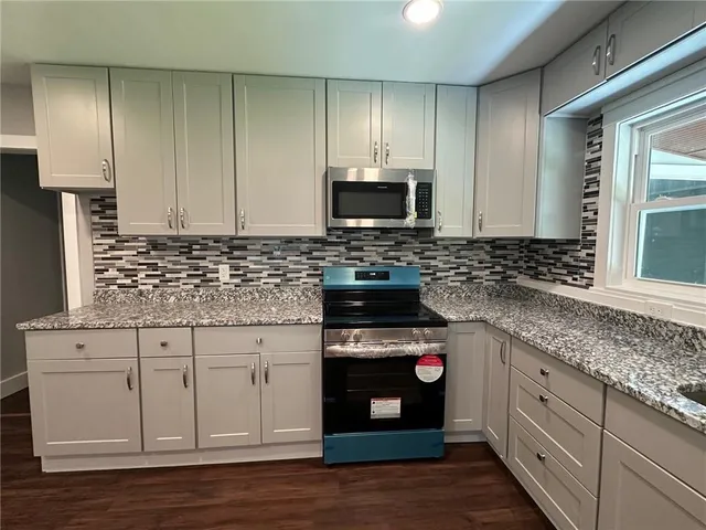 a kitchen with stainless steel appliances granite countertop a stove a sink and a microwave