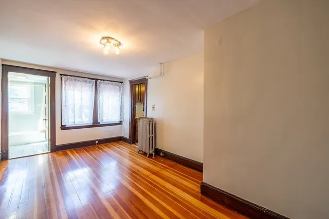 a view of an empty room with window and wooden floor