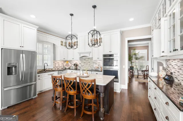 a kitchen with stainless steel appliances a dining table chairs stove and refrigerator