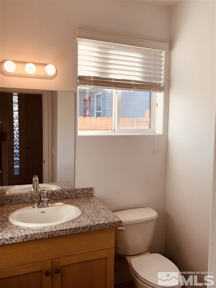540 Warren Court Reno, NV 89509 - Photo 7 of 17 a bathroom with a granite countertop toilet a sink and a mirror