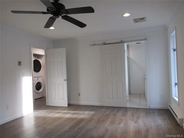 wooden floor in an empty room with a window and a ceiling fan