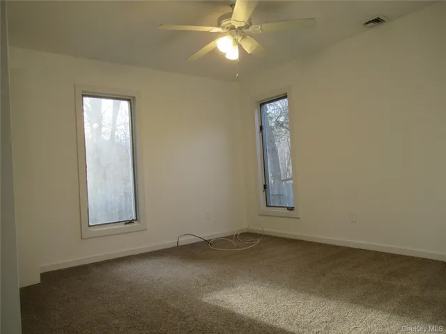 an empty room with windows and fan