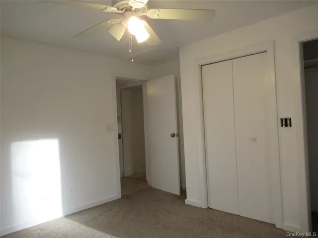 an empty room with a chandelier fan and closet area