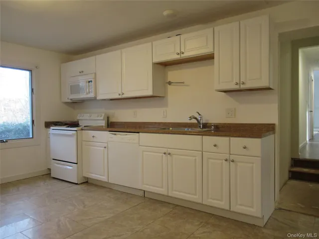 a kitchen with white cabinets and white appliances