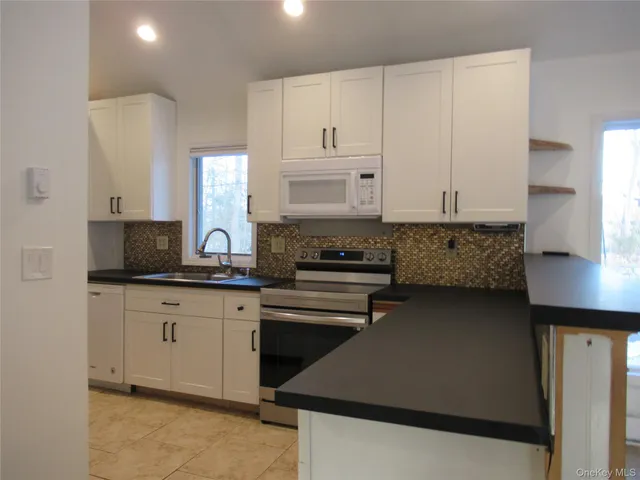 a kitchen with stainless steel appliances granite countertop a stove a sink and a white cabinets