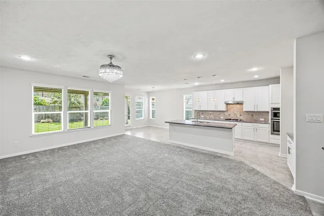 a large kitchen with granite countertop a sink and white cabinets