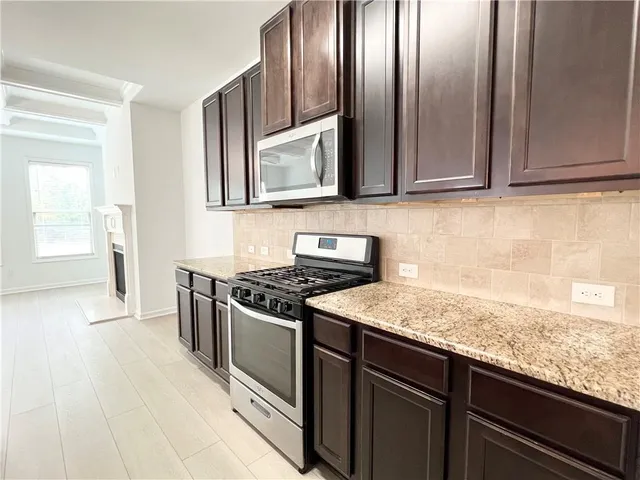 a kitchen with granite countertop stainless steel appliances a stove microwave and sink