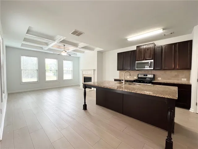 a kitchen with stainless steel appliances granite countertop a stove a sink dishwasher and a microwave oven with cabinets