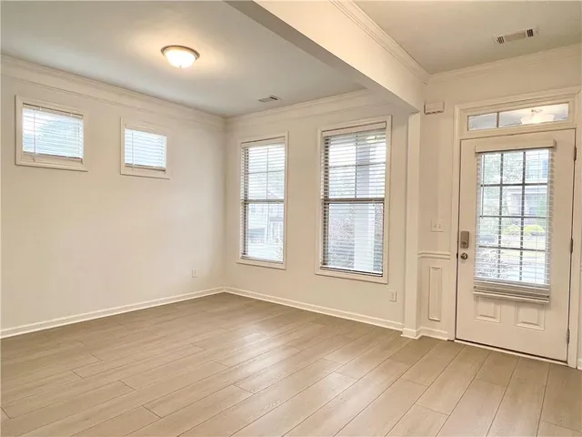 an empty room with wooden floor and windows