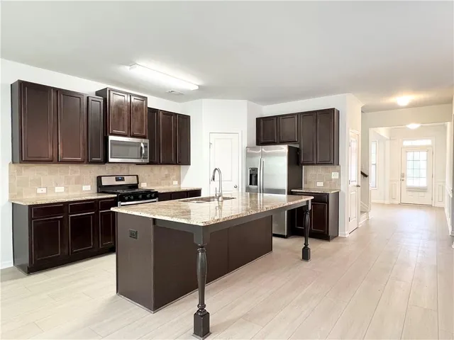 a kitchen with stainless steel appliances a sink a stove a refrigerator cabinets and a center island