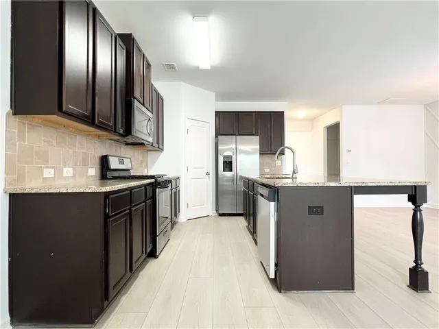 a kitchen with stainless steel appliances granite countertop a refrigerator a sink a stove and oven